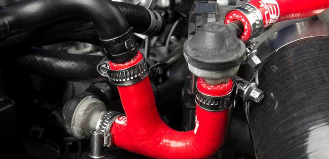 Red silicone tubes installed in an automotive engine system with stainless steel clamps